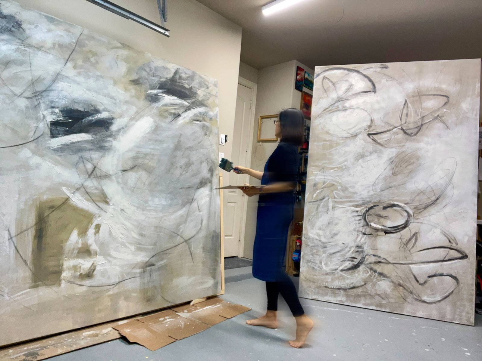 Joanna Purvis at work between two large canvases in her studio