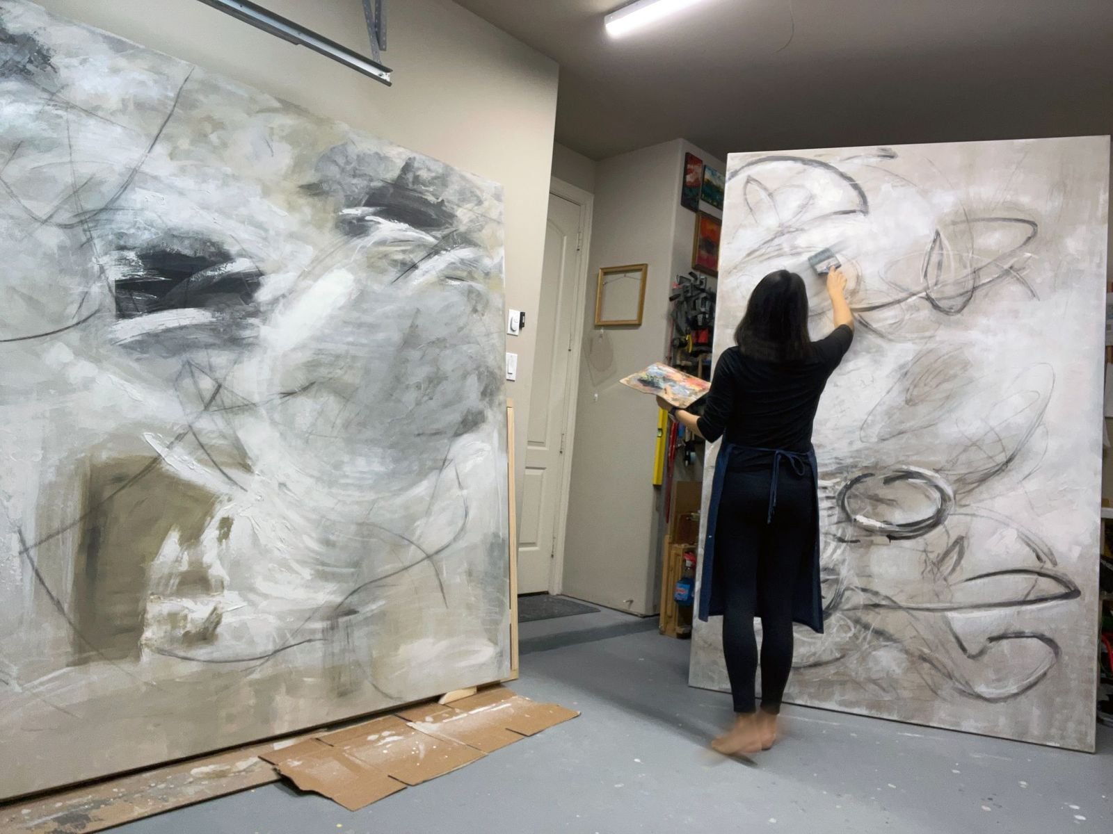 Joanna Purvis painting two large canvases in her Houston studio